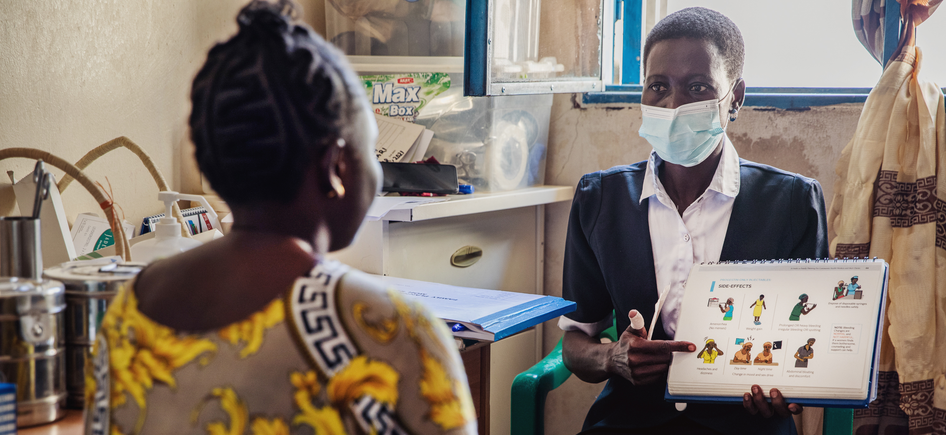 A South Sudanese health advocate explains health information with a chart to a patient