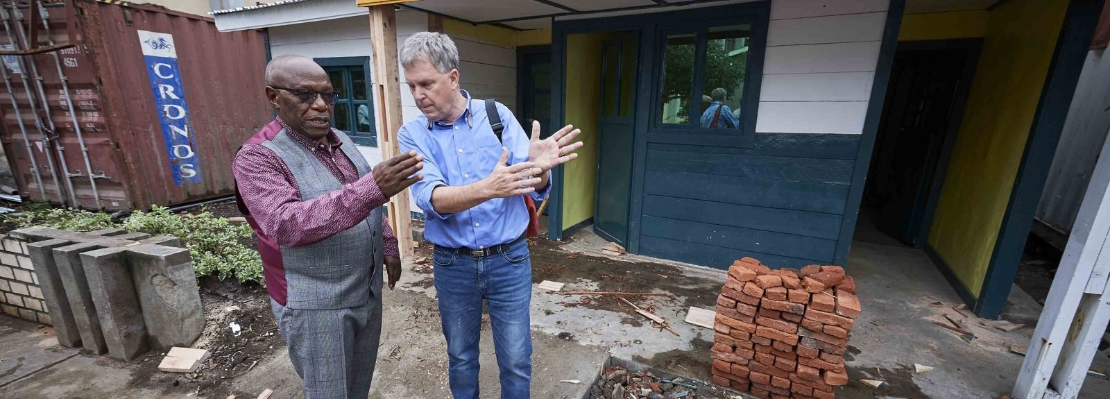 Dr. Kasereka “Jo” Lusi (left), an orthopedic surgeon who founded HEAL Africa, consults with Dr. Bill Clemmer, who led the Ebola response for IMA World Health, stand in front of an isolation unit for suspected Ebola patients at the entrance to the Heal Africa Hospital in Goma, the war-torn city in the eastern Democratic Republic of the Congo in 2019. The doctors are now working together to respond to COVID-19. (Photo by Paul Jeffrey)