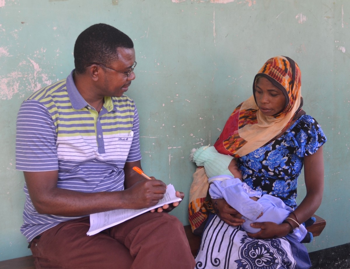 IMA World Health program manager and a trachoma patient and her baby discuss treatment