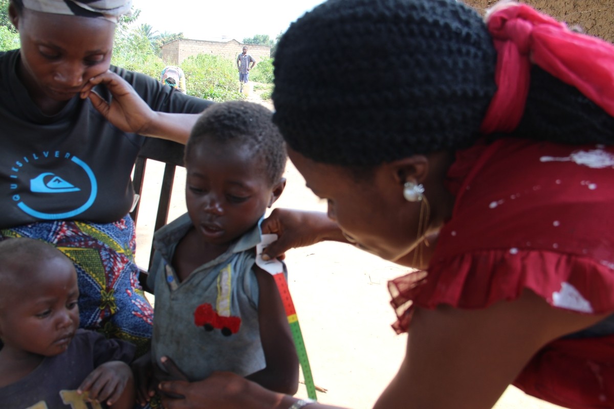 A community health worker screens for child malnutrition in the DRC through IMA World Health's MOMENTUM Integrated Health Resilience project.