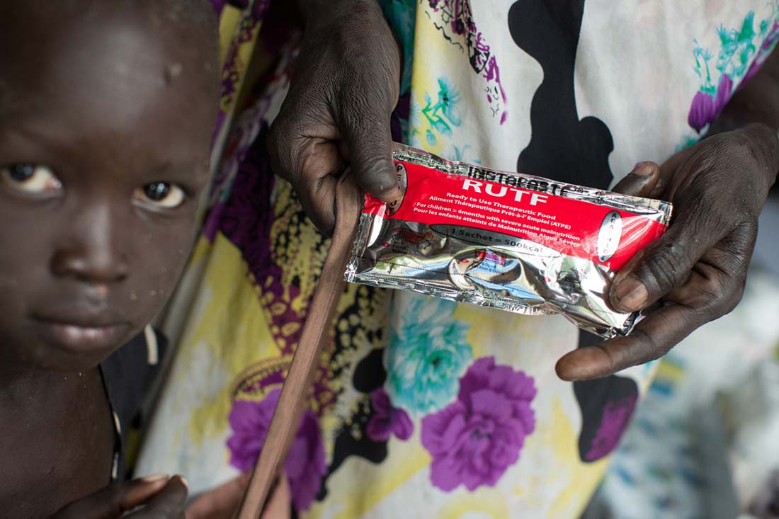 A mother and child receive packets of "Ready-to-Use Therapeutic Food"-- a vitamin and mineral fortified peanut paste mixed with dry milk given to malnourished children-- at the John Dau Foundation compound in Duk Padiet in South Sudan's Jonglei state, September 29, 2017. Lutheran World Relief has partnered with IMA World Health and in turn, the John Dau Foundation, to set up and run three life-saving medical stabilization centers, including one that will be installed on this site, for the treatment of young children and lactating mothers at risk of death from starvation. The project, called “Providing Emergency Nutrition Services in South Sudan” will reach just under 100,000 individuals. (photo by Allison Shelley for Lutheran World Relief)