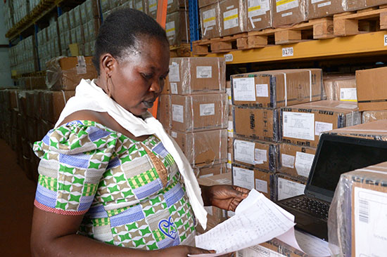 Lily Kaku, of the South Sudan Ministry of Health's Central Medical Store, checks inventory against a spreadsheet in preparation for distributing supplies. (Photo by Matt Hackworth/IMA World Health)