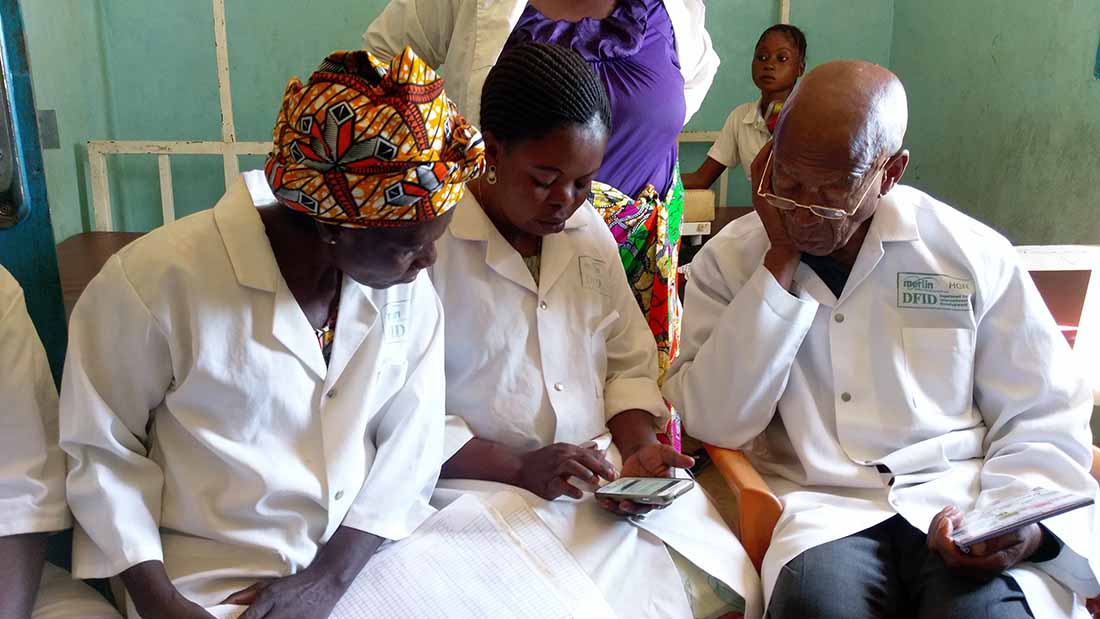The personnel at Basoko Health Center in Kindu Health Zone in the Democratic Republic of Congo learn how to use the smartphone app. On the right is Raphael Odimba, Head Nurse at the health center, sitting next to Anjelani Imurani, Head of Maternity at Basoko. (Photo by Davis Makasy/IMA World Health)