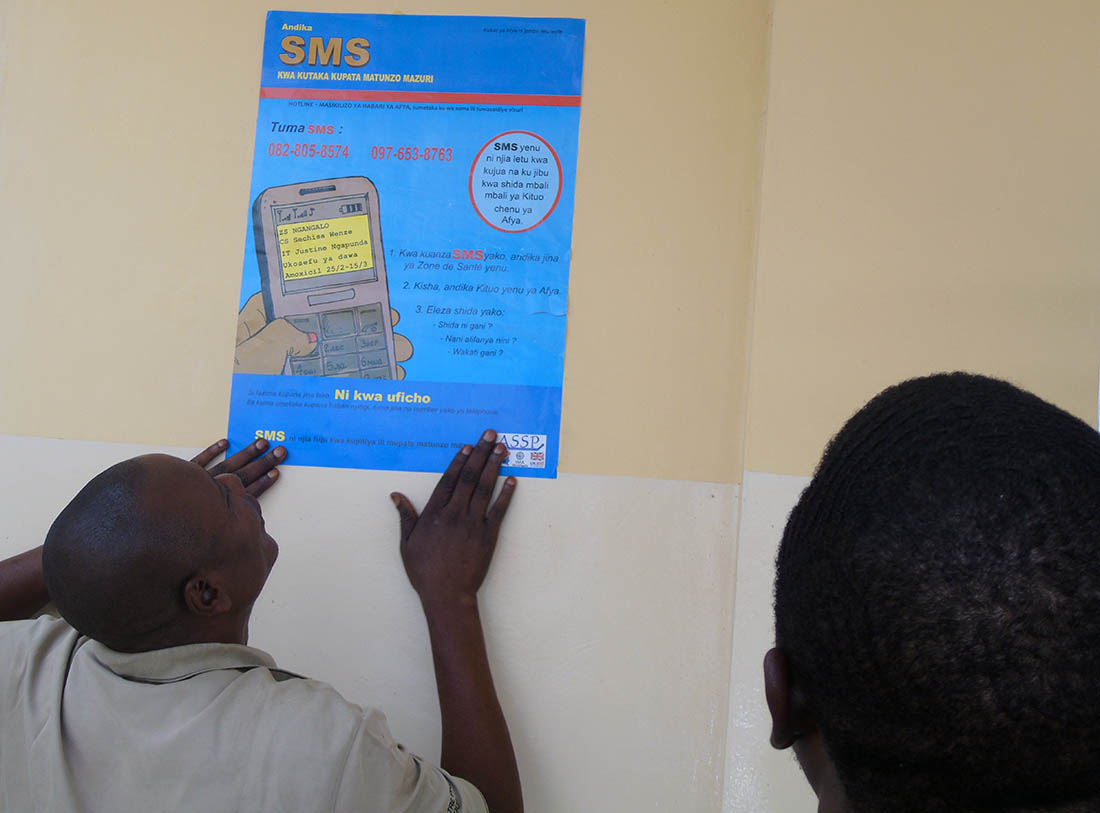 Olivier Cianyi hangs a Hotline poster in the Central Office of the Health Zone in Kindu on August 20, 2018.